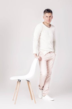 yakışıklı genç adam beyaz kazaklı bir sandalyeye oturur