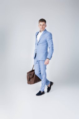 Deri çanta tutan mavi elbiseli genç adam