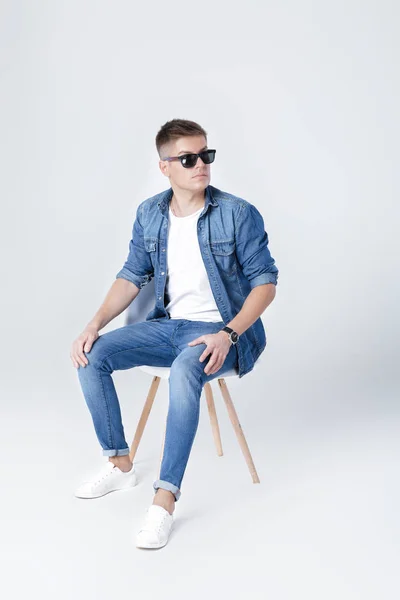 Hombre guapo en denim se sienta en la silla — Foto de Stock