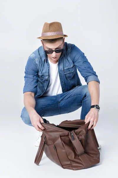 Hombre sorprendido en un sombrero mira en una bolsa de cuero vacía . —  Fotos de Stock