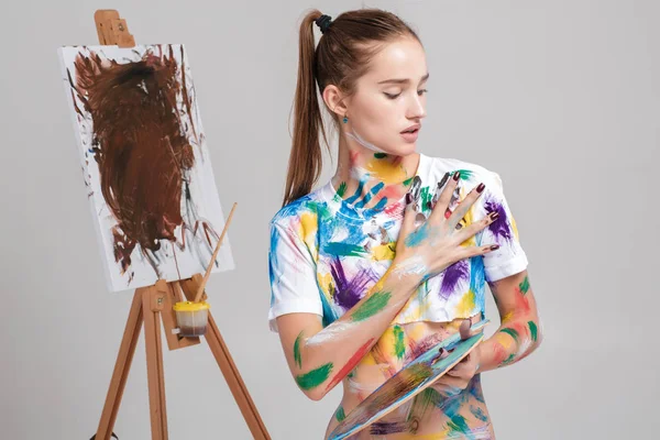 Pelukis wanita kotor dalam gambar cat berwarna-warni di atas kanvas . — Stok Foto