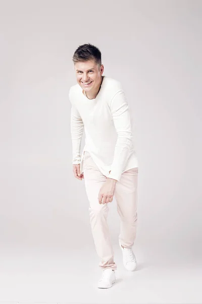 Красивый молодой человек в белом свитере и брюках — стоковое фото