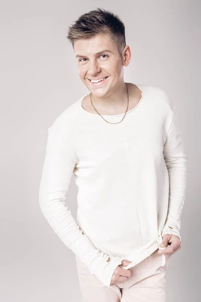 Knappe jonge man in een witte trui en broek — Stockfoto