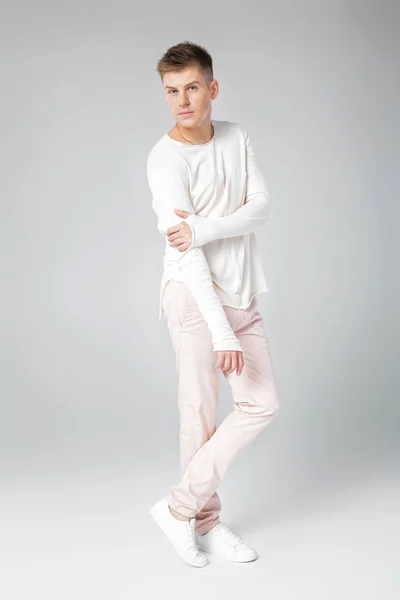 Bello giovane uomo in un maglione bianco e pantaloni — Foto Stock