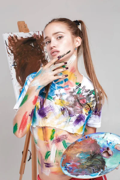 Kvinna målare smutsiga i färgglada paint ritar på duk. — Stockfoto