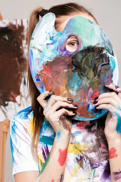 Woman artistholds  palette with paints in front of face — Stock Photo, Image