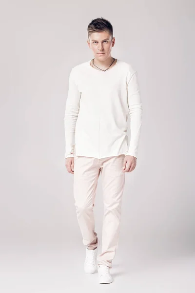 英俊的年轻男子，穿着一件白色的毛衣和裤子 — 图库照片