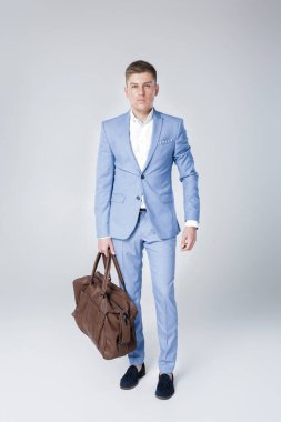 Deri çanta tutan mavi elbiseli genç adam