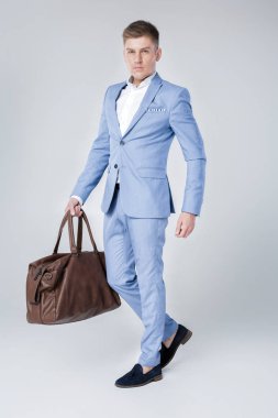 Deri çanta tutan mavi elbiseli genç adam