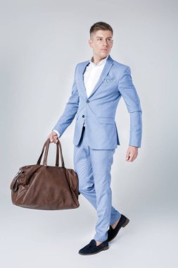 Deri çanta tutan mavi elbiseli genç adam