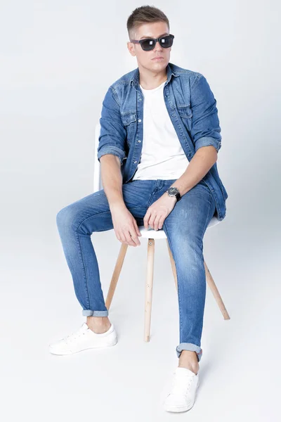 Красивий чоловік в джинсах сидить на стільці — стокове фото