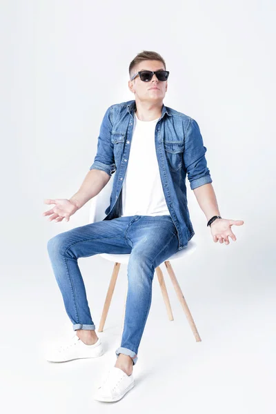 Красивий чоловік в джинсах сидить на стільці — стокове фото