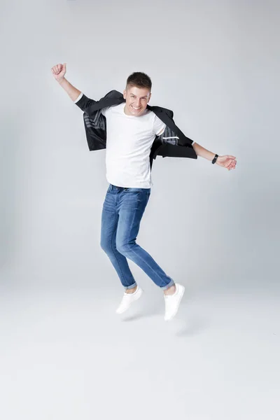 Homem bonito em jeans e casaco pulando — Fotografia de Stock