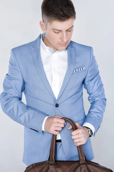 Модный молодой человек в синем костюме с кожаной сумкой — стоковое фото
