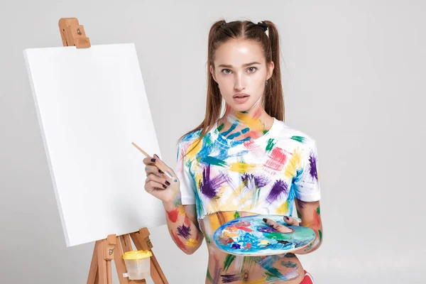 Woman painter soiled in colorful paint draws on canvas. — Stock Photo, Image