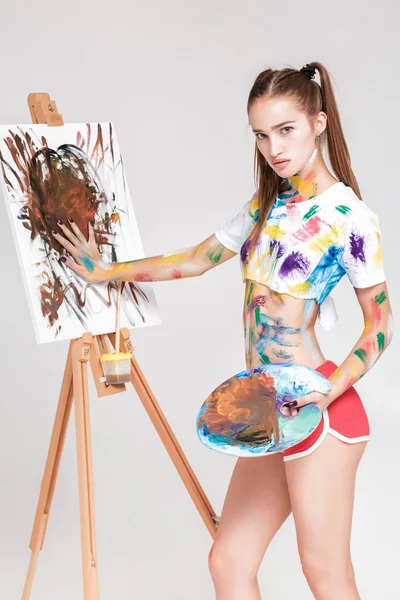 Femme peintre souillé dans la peinture colorée dessine sur toile . — Photo