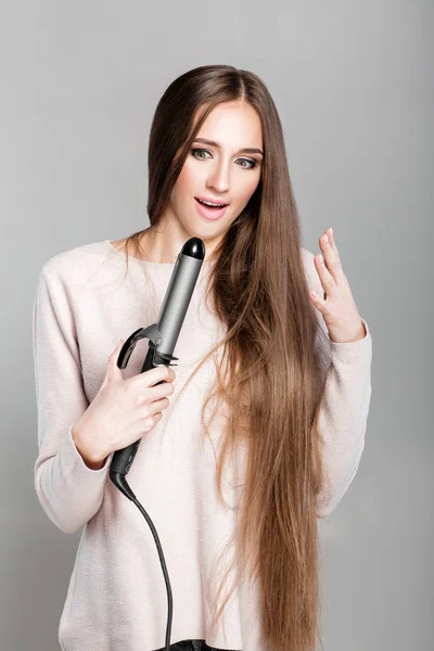 woman using curling iron.