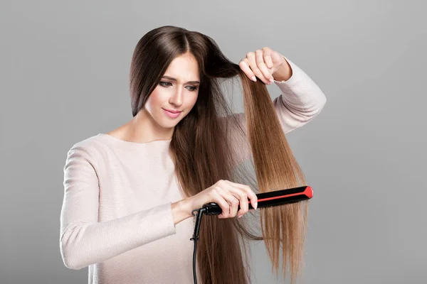 Mulher engomar cabelo com ferro de cabelo . — Fotografia de Stock