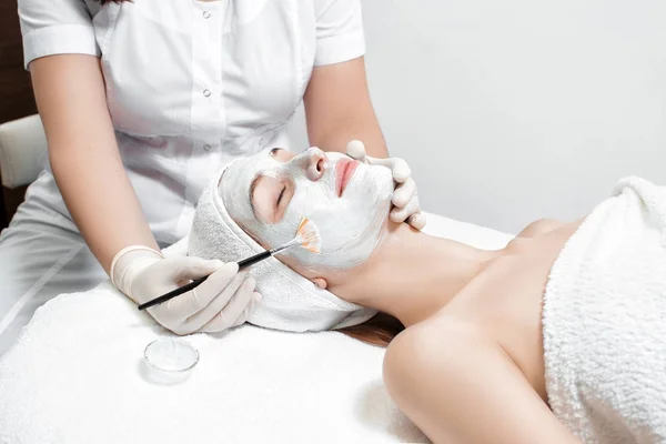 beautician applies mask to the face of  woman