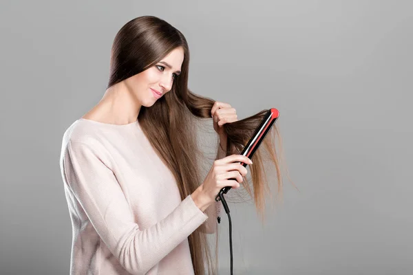 Mujer planchar el cabello con plancha de pelo . —  Fotos de Stock