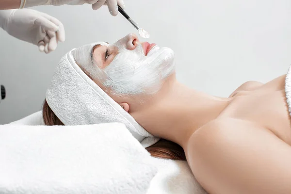 Esteticista aplica máscara para o rosto da mulher — Fotografia de Stock