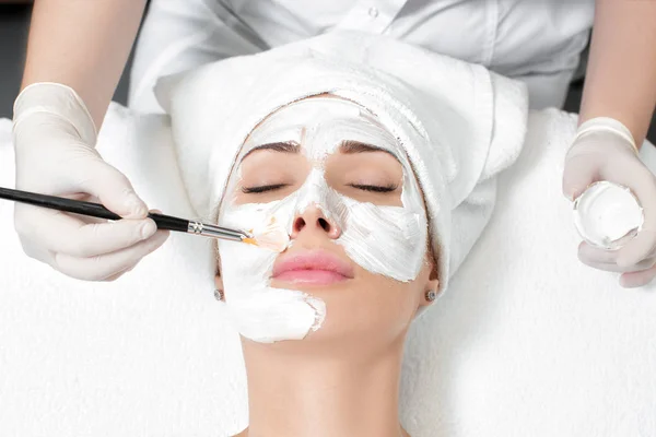 美容師は、女性の顔にマスクを適用します。 — ストック写真