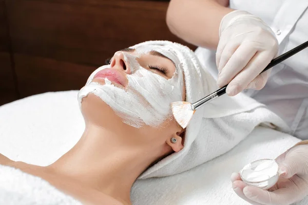 美容师在女人脸上应用面具 — 图库照片