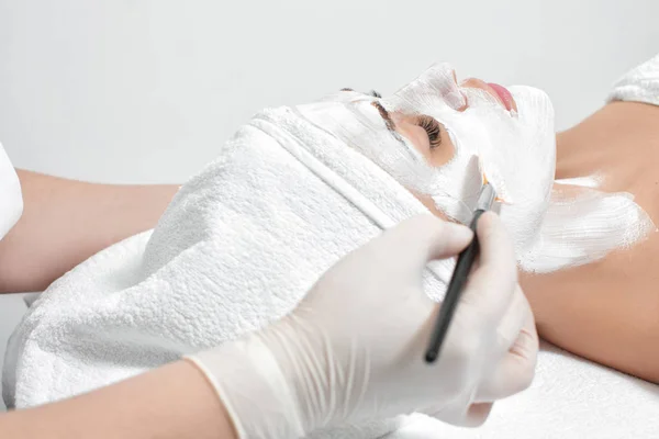 Esteticista aplica máscara a la cara de la mujer — Foto de Stock