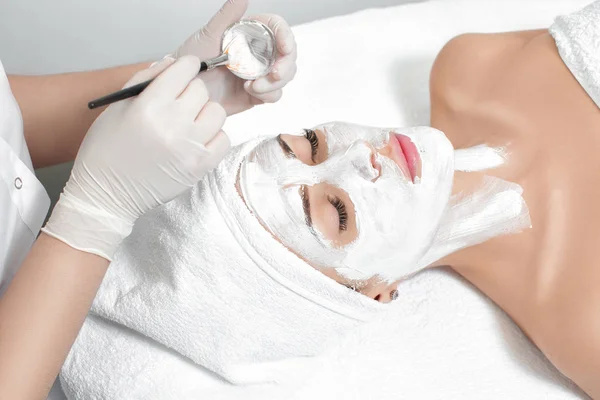 beautician applies mask to the face of  woman