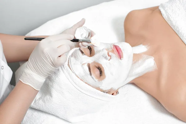 Schoonheidsspecialiste toepassing masker op het gezicht van de vrouw — Stockfoto