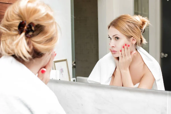 Woman looks at herself in the bathroom mirror — Stock Photo, Image