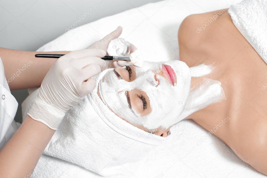 beautician applies mask to the face of  woman
