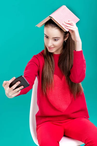 Ragazza legge libro e utilizza smartphone . — Foto Stock