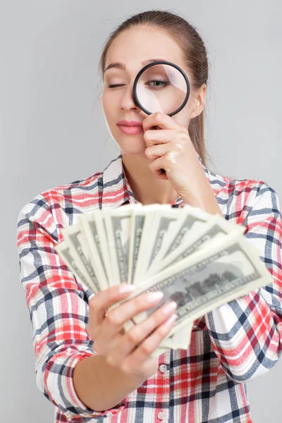 Mujer mira en lupa en billetes de dólar — Foto de Stock