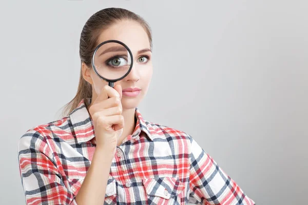 Woman looks through a magnifying glass — Stock Photo, Image