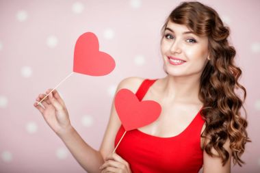 Kadın pembe bir arka plan üzerinde kırmızı kalp.