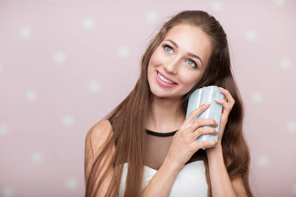 woman holds gift box on pink background.