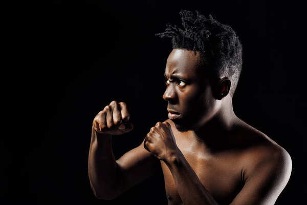 Portrait of an African-American athlete man boxing on black background