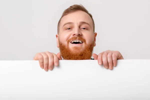 Homem com barba segurando grande cartão branco . — Fotografia de Stock