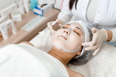 güzellik uzmanı bir maskeyi yüzüne koyar.