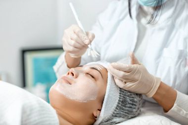 güzellik uzmanı bir maskeyi yüzüne koyar.