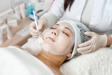 güzellik uzmanı bir maskeyi yüzüne koyar.