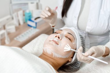 güzellik uzmanı bir maskeyi yüzüne koyar.