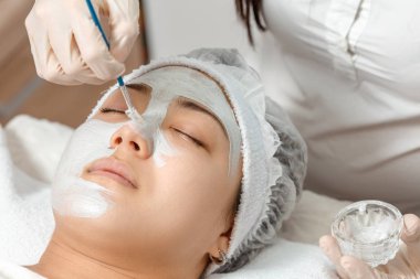 güzellik uzmanı bir maskeyi yüzüne koyar.