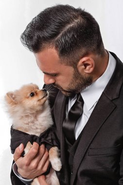 siyah elbiseli adam pomeranian köpek tutar