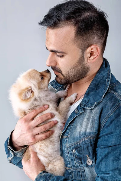 Hombre en chaqueta de mezclilla sostiene perro pomerania . — Foto de Stock