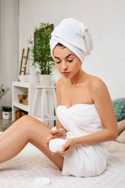 Woman in towel applying cream on her hands — Stock Photo, Image