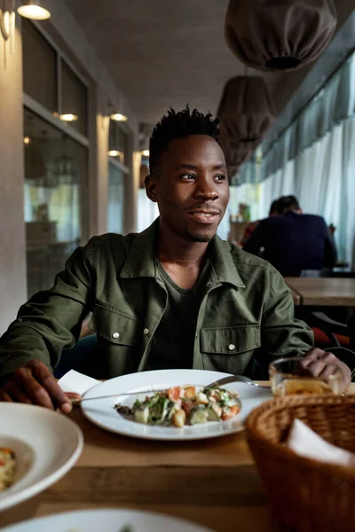 Giovane uomo africano americano sta mangiando in un ristorante — Foto Stock