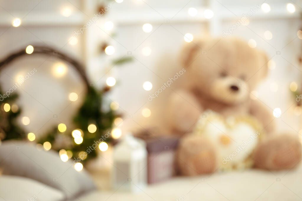 blur background of christmas wreath and teddy bear with lights garland.