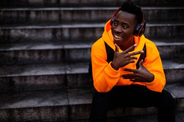 Kablosuz kulaklıklı, müzik dinleyen Afro-Amerikan bir adam.